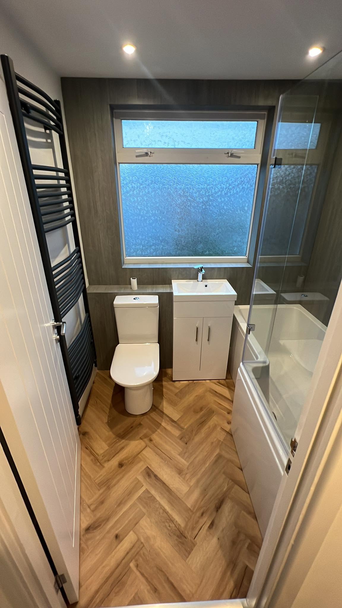 Oak herringbone floor in a bathroom with a white suite