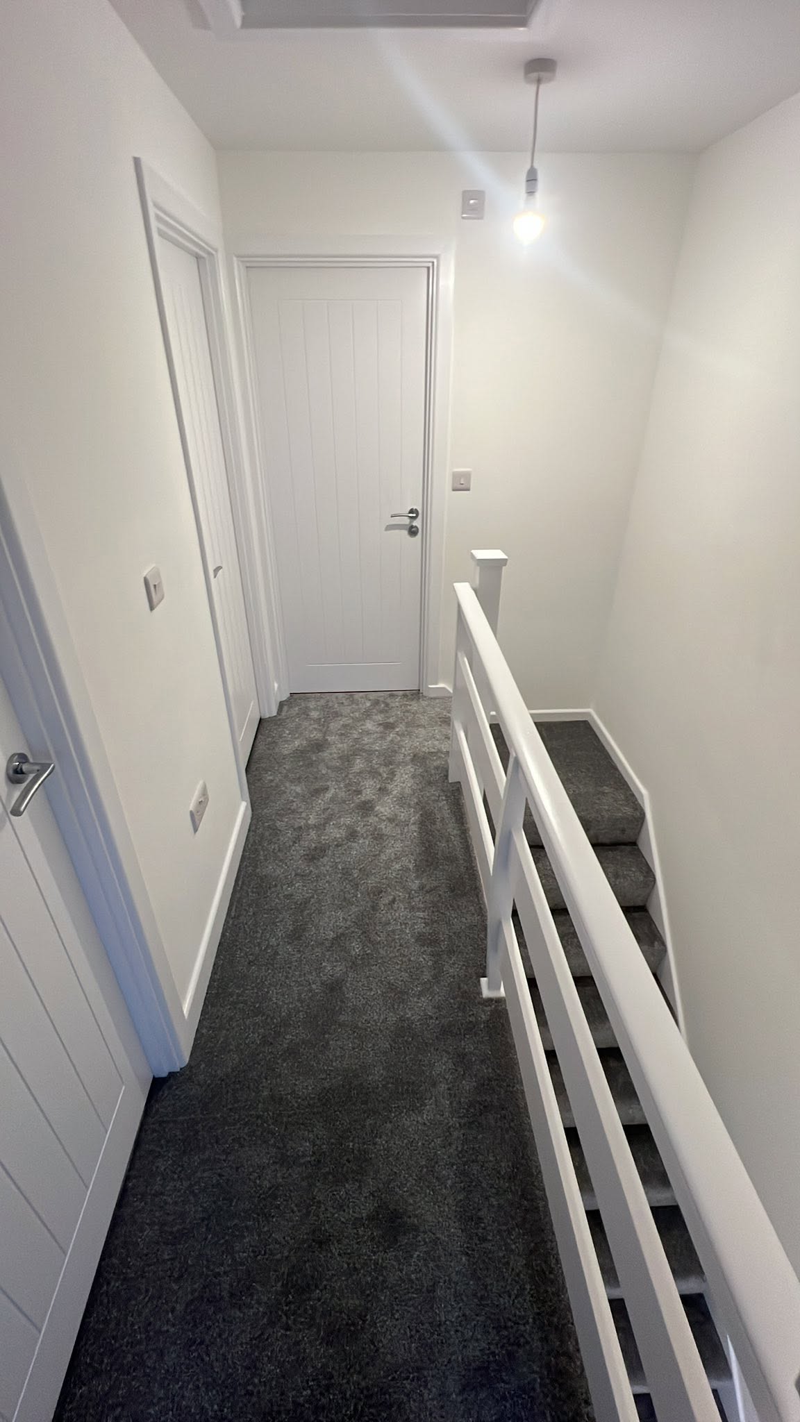Charcoal carpet along a landing with white banisters