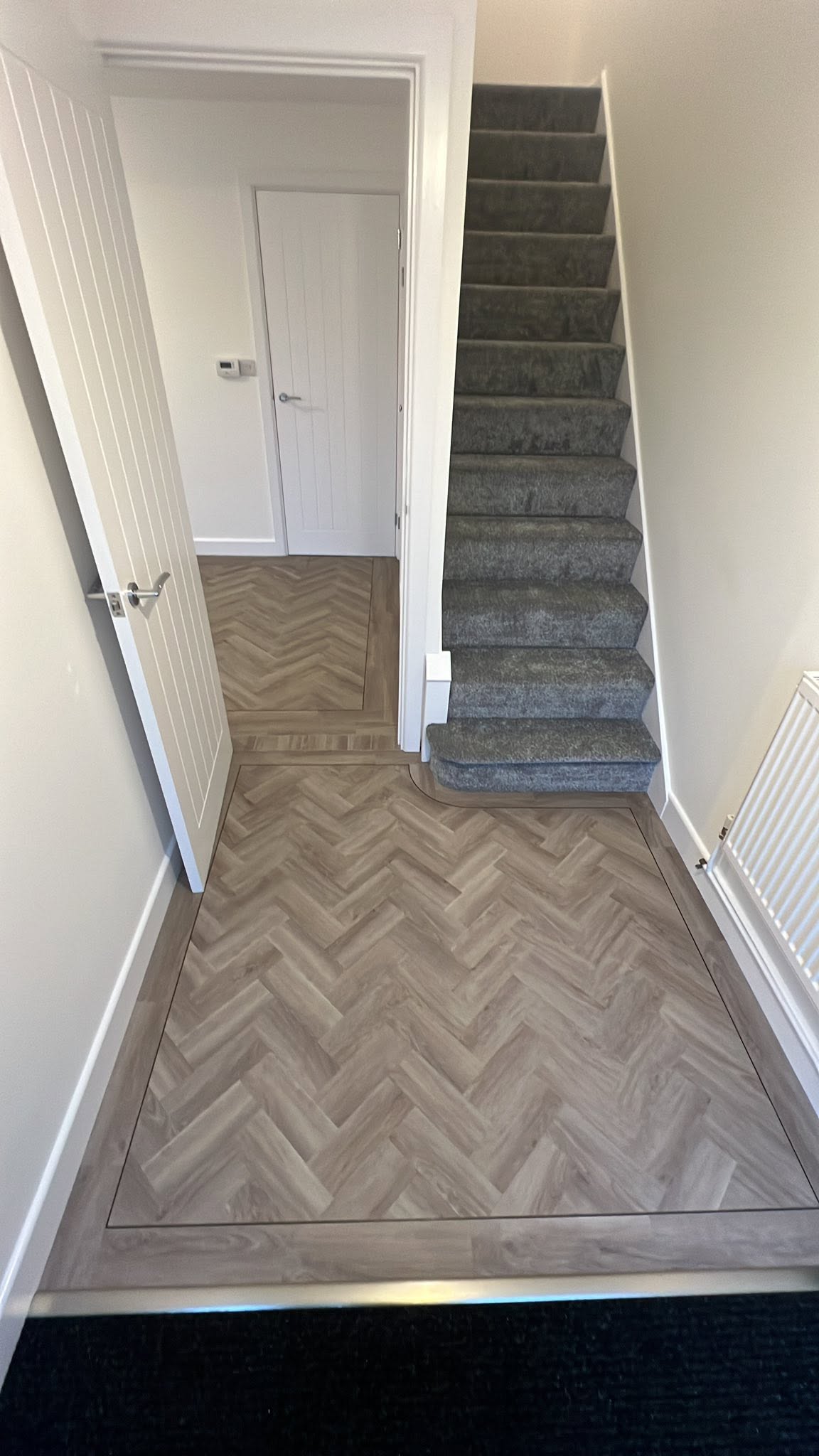 Hall herringbone with carpeted stairs and an inset mat