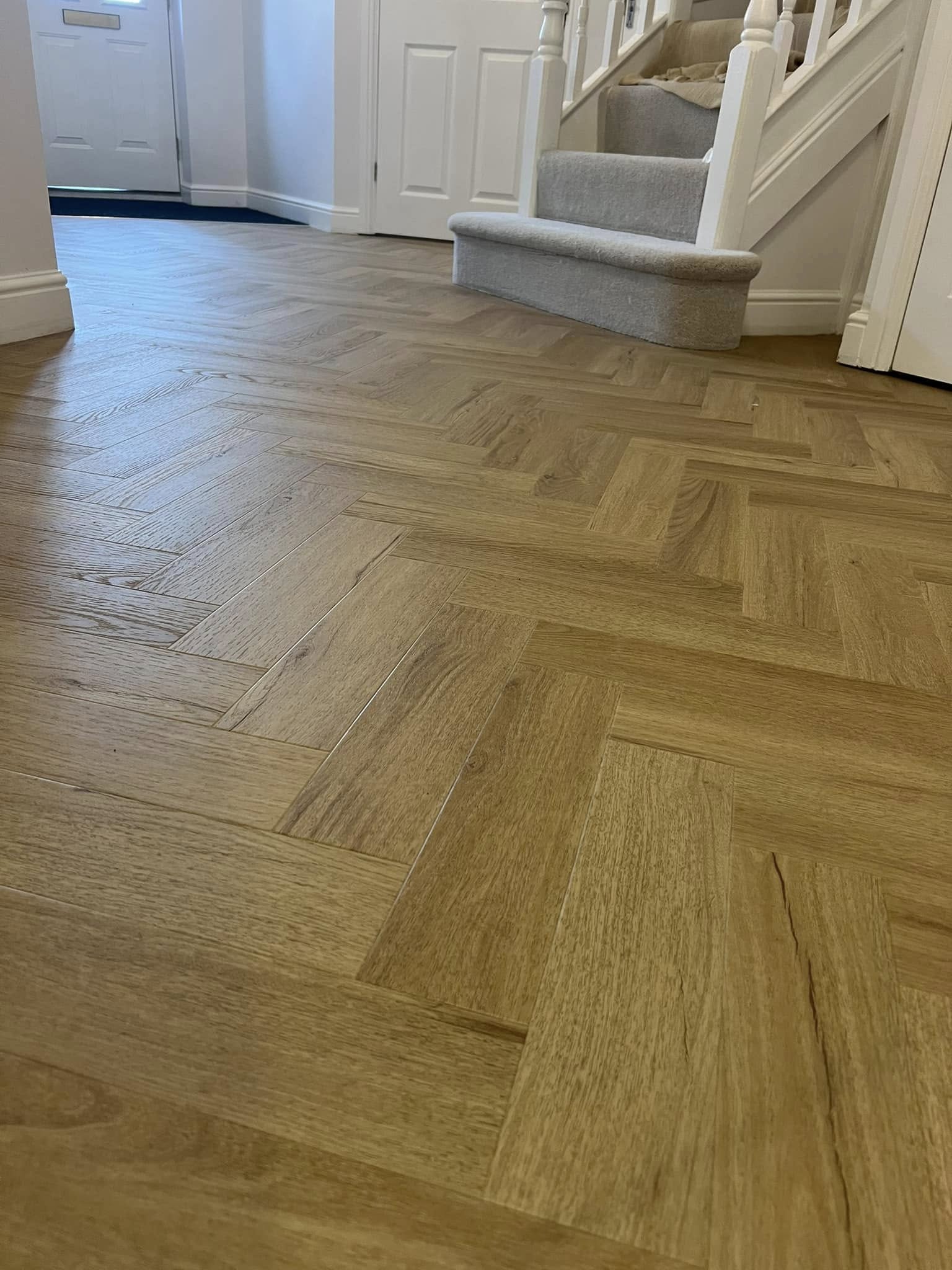 Golden herringbone in a hall at the foot of carpeted stairs