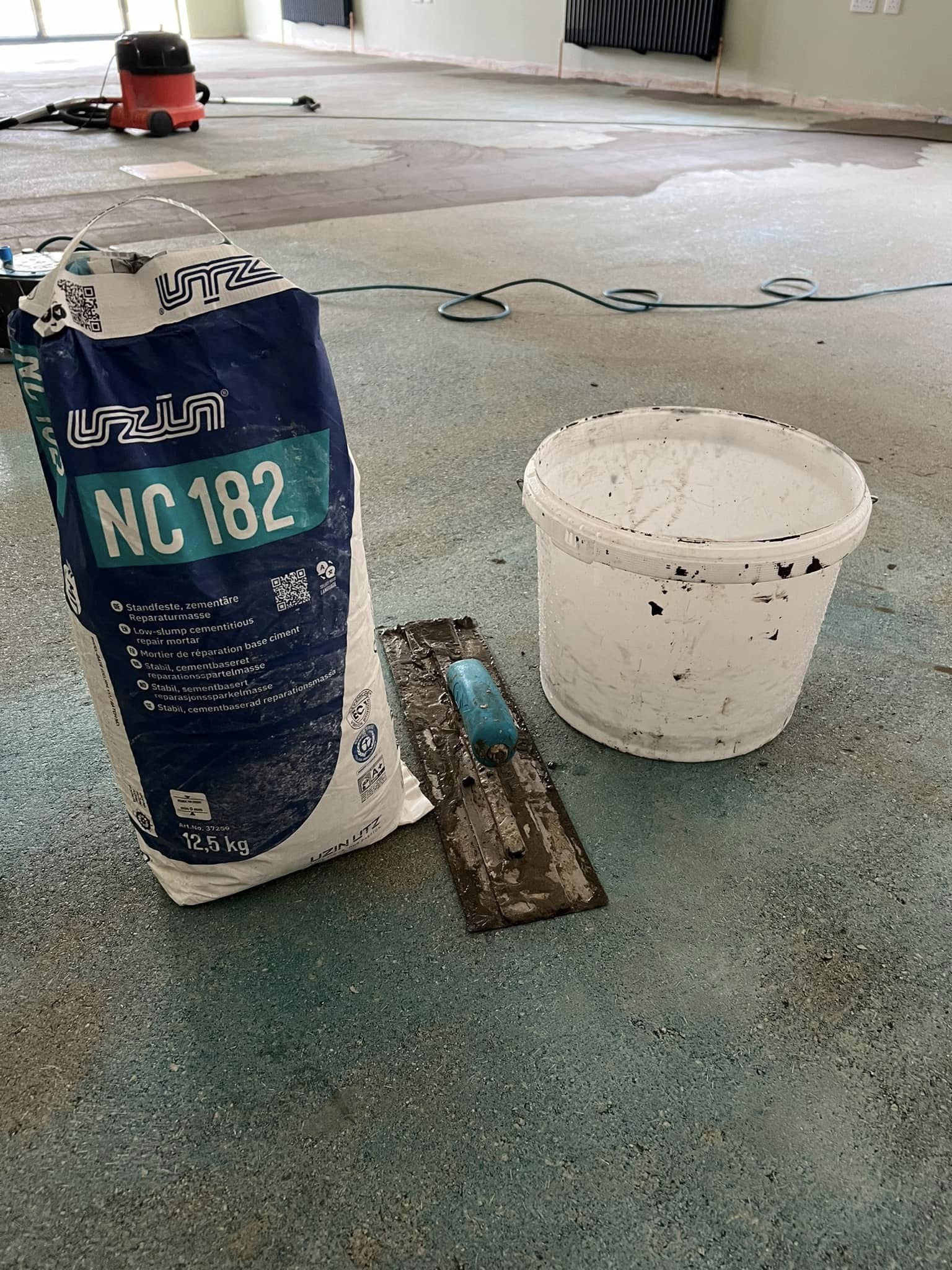 Bag of levelling compound and a bucket on the floor