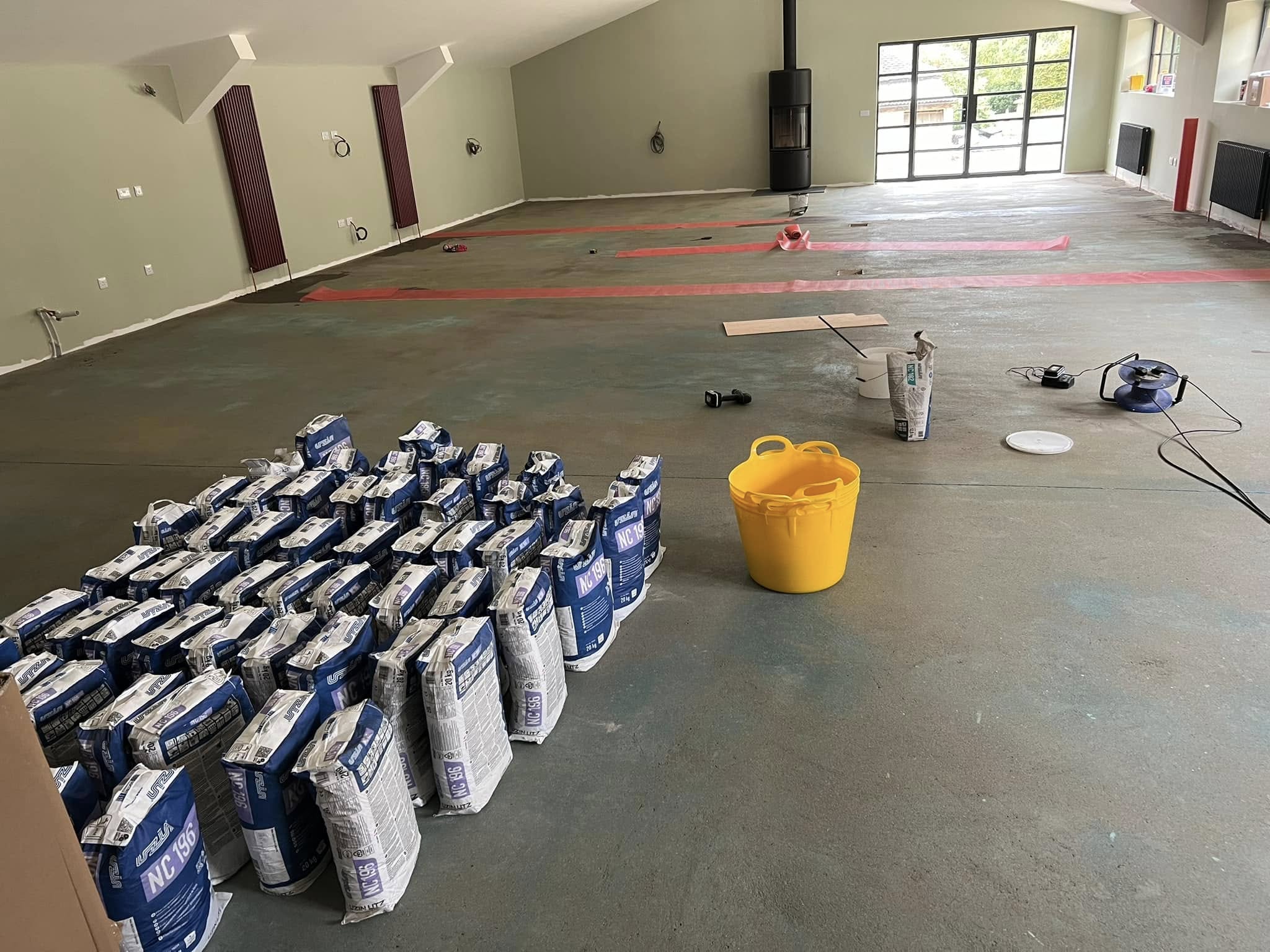 Stacked bags of levelling compound on the primed floor