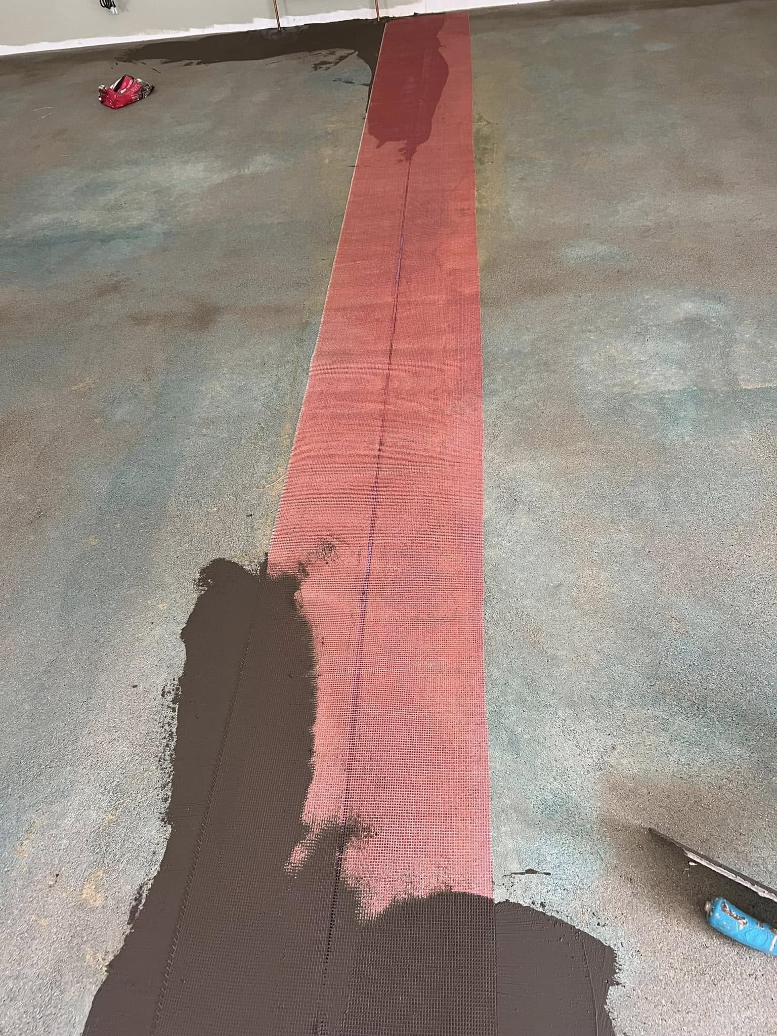 Close-up of red mesh tape over a crack, partly covered with compound