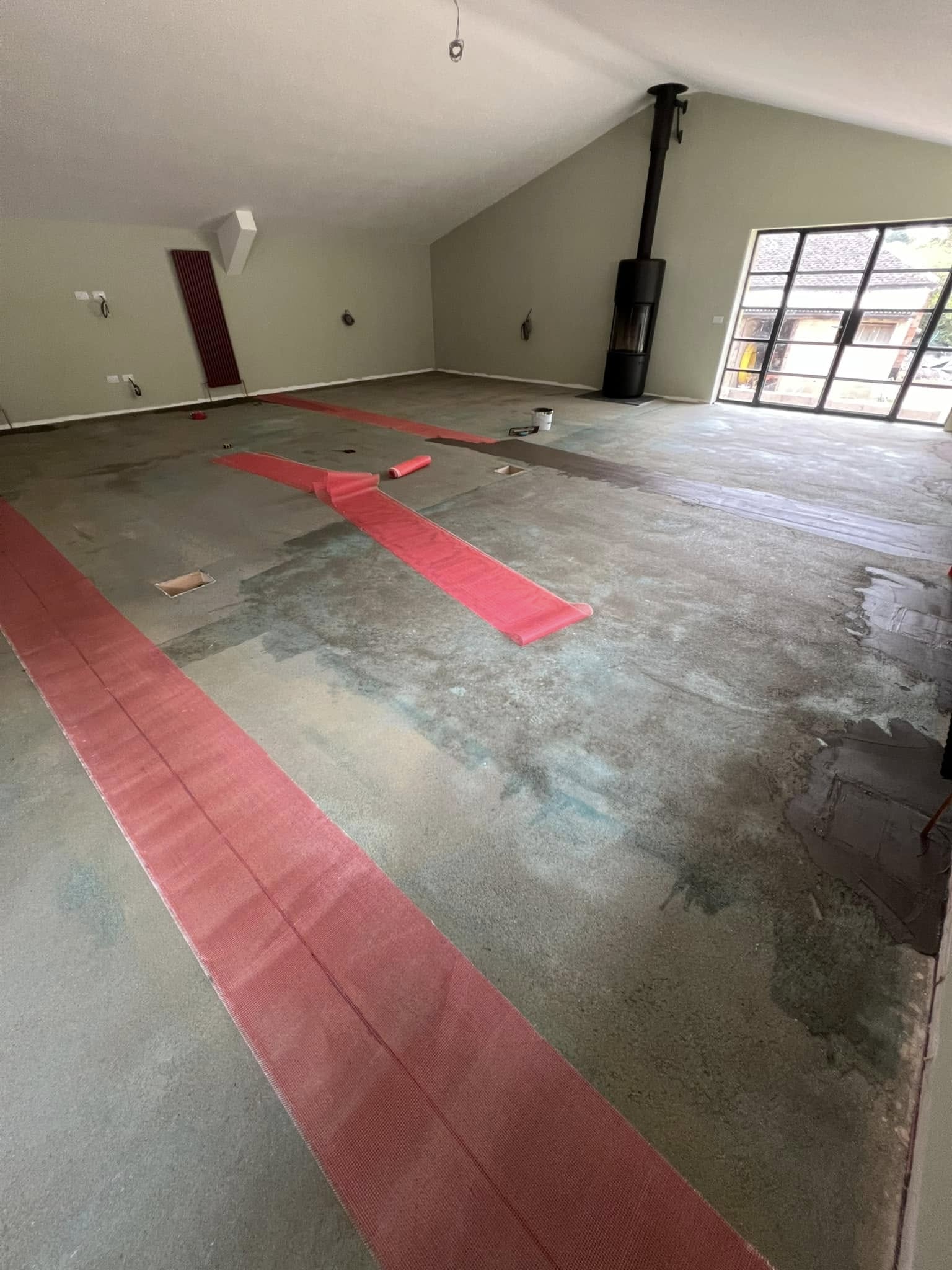 Long room with red mesh tape laid across cracks in the concrete floor