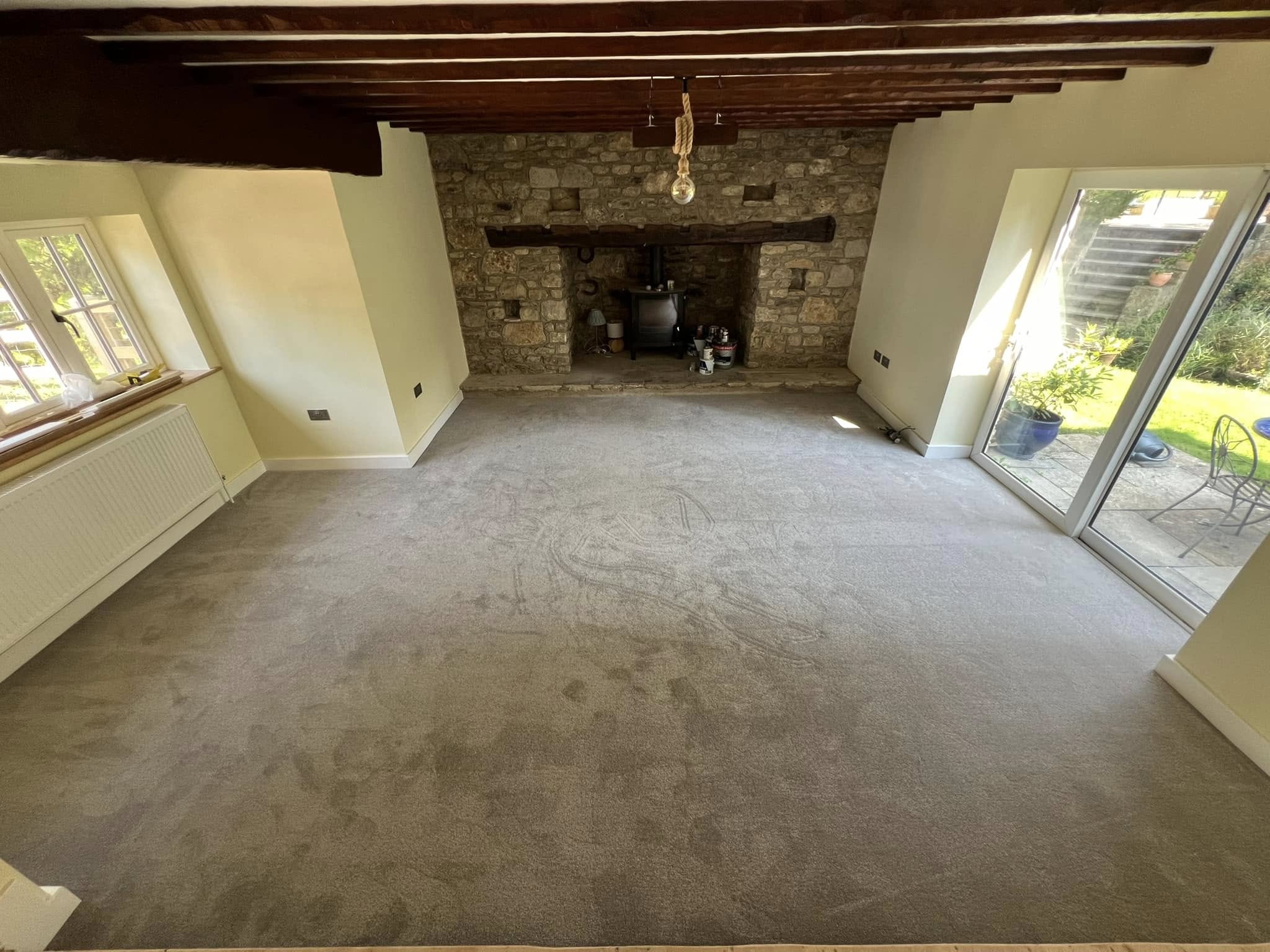 Grey carpet in a beamed lounge with a stone inglenook fireplace