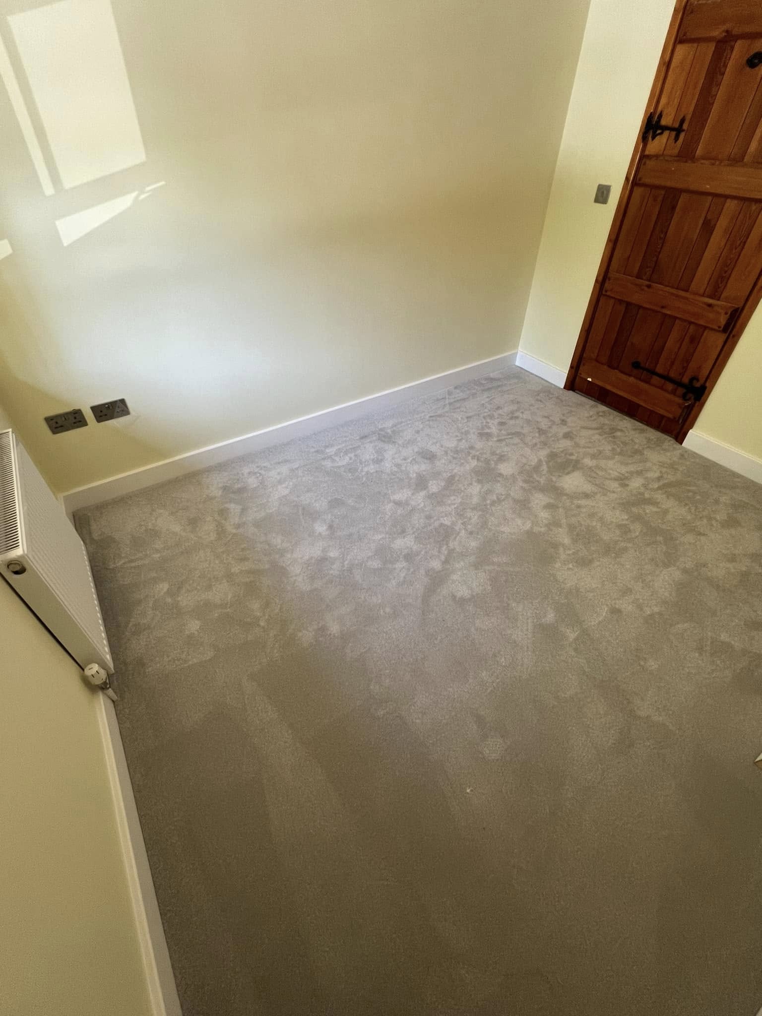 Grey carpet in a cottage bedroom with a wooden door
