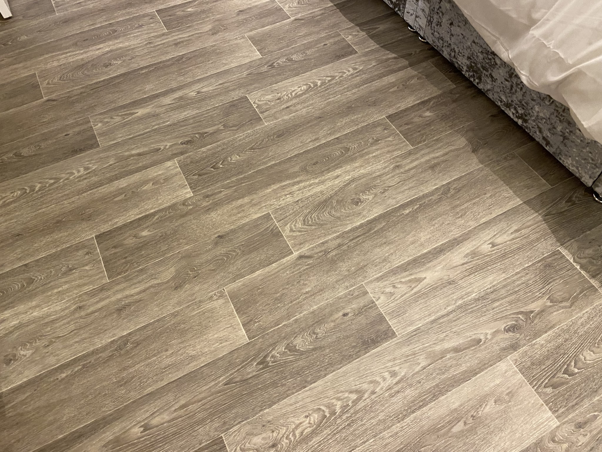 Grey plank-effect vinyl beside a bed