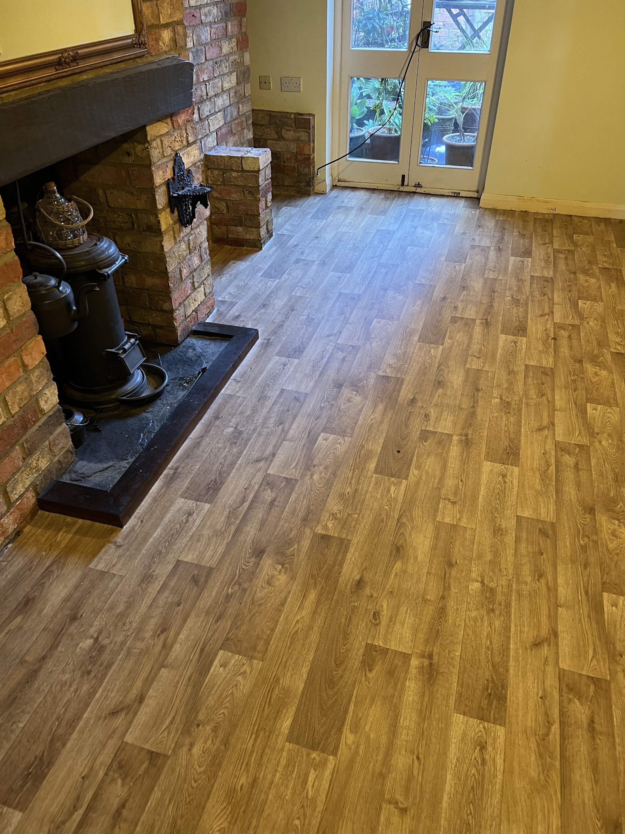 Oak-effect plank floor beside a brick fireplace and stove