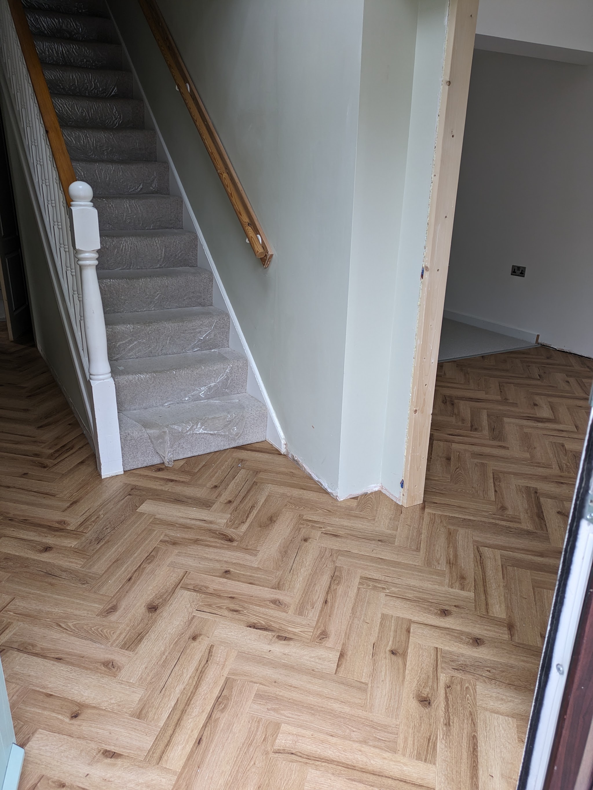 Herringbone hallway with freshly carpeted stairs