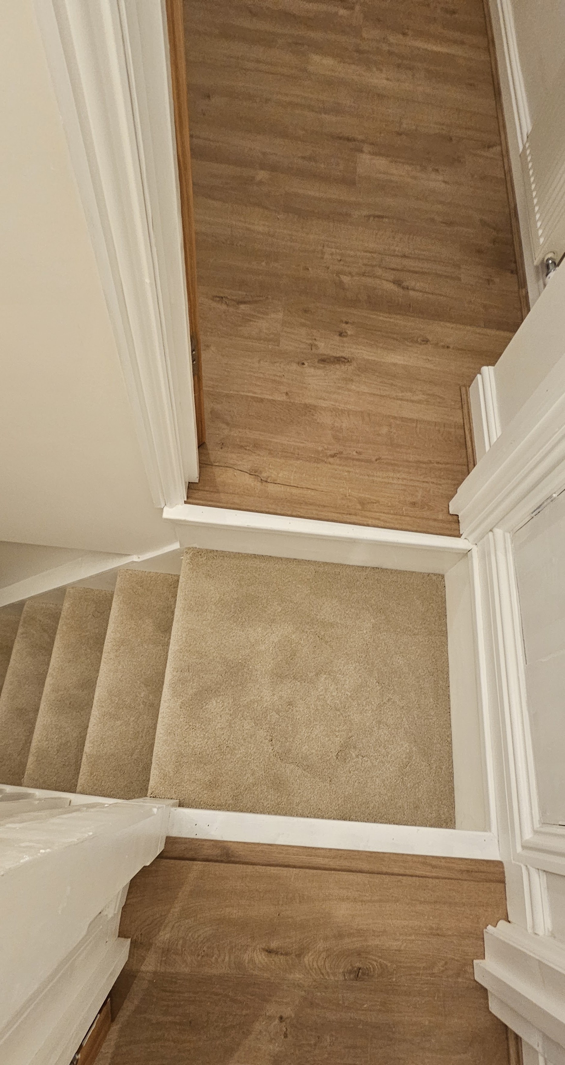 Oak-effect landing above beige carpeted stairs